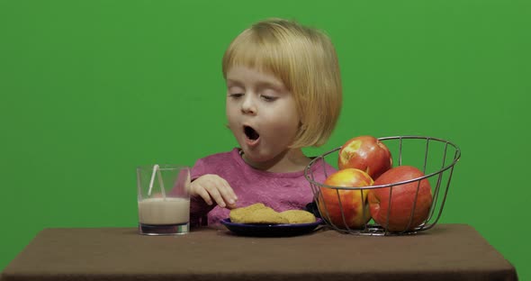 Girl Sitting at the Table and Eating Chocolate, Cookies and Drinks Cacao