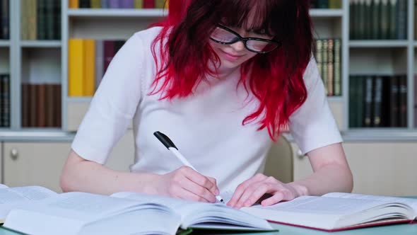 Teenage Girl Student with Glasses Studying in the School Library