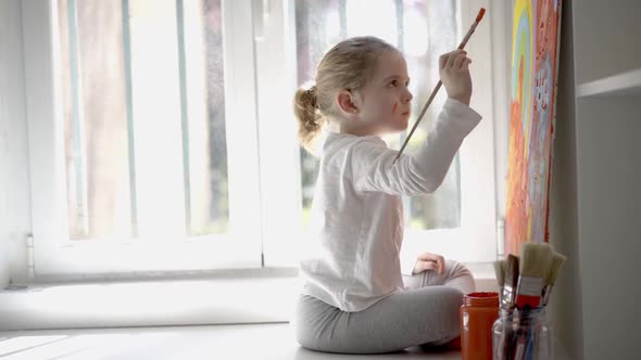Little girl painting picture with paintbrush