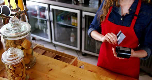 Waitress swiping credit card at counter