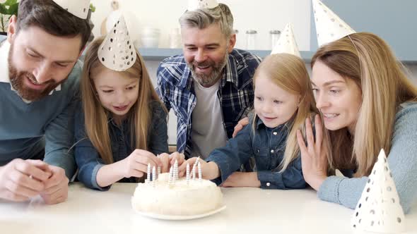 Parents Looking at Girls Putting Candles on Birthday Cake