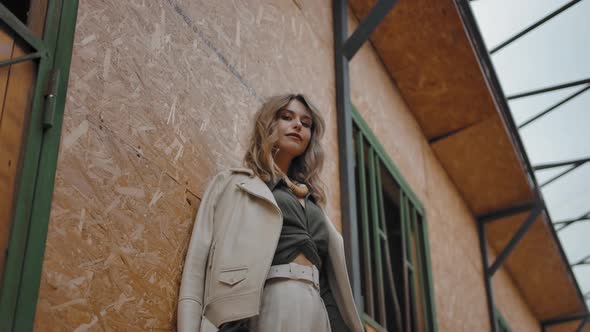 Trendy Female Leaning on Wall of Stable