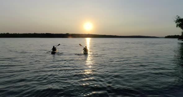 Two kayaks with people on the river on the scenic sunset