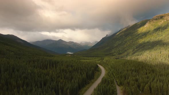 View of Scenic Road Alongside Peaceful Lake Surrounded By Mountains