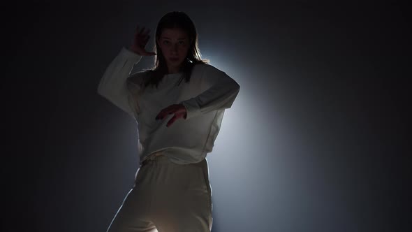 Talented Woman Dancing Hip Hop on Background with White Light in Studio