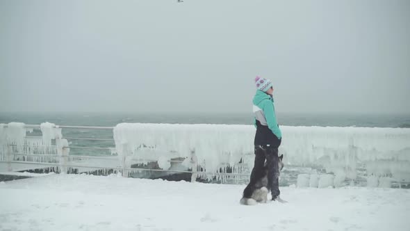 Young Female Playing and Runing with Siberian Husky Dog on the Beach at Snow Storm Slow Motion