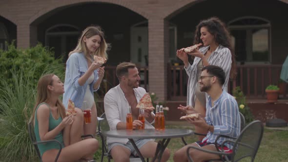 Group of happy young people cheering with cider by the pool in the garden