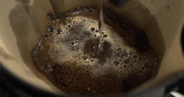 Dripping hot water over ground coffee in filter. Coffee brewing in slowmotion