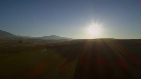 Aerial view of beautiful hills with lots of grass and the sun shining.