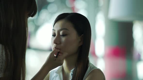 Makeup artist applying lipstick on womens lips