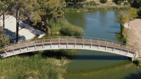 Aerial Pull Back of a picturesque wooden bridge in a park, Lancaster, California