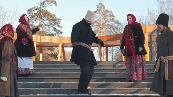 Russian Folk - Men and Women in Traditional Russian Clothes Are Dancing on the Stairs in Winter