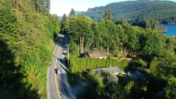 Drone shot over small town with houses , roads, lake and mountains