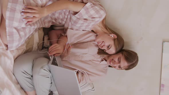 Vertical Shot of Twin Sisters Watching Movie on Laptop