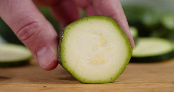 The Hand of a Man with a Knife Cut Zucchini Into Pieces. 