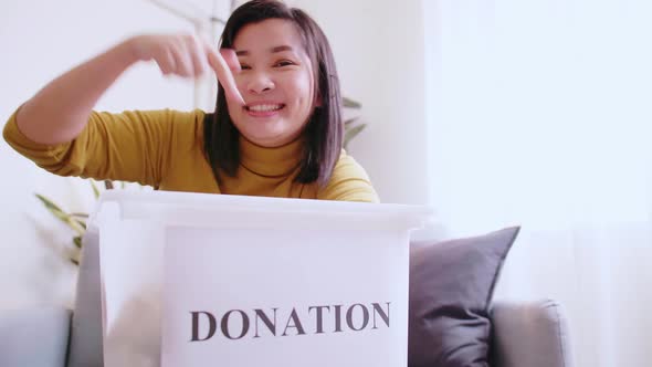 Lovely woman pointing to box with donations, inviting others to donate too.