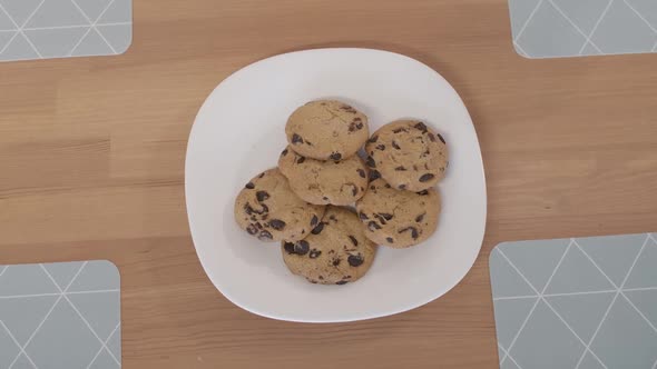 Top View of Plate with Cookies on the Table with Children's Hands Taking Sweet Biscuits Leaving It