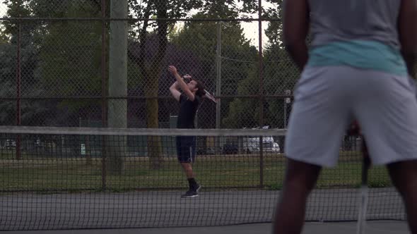 Caucasian Male Unsuccessfully serves his black Male opponent at a local community tennis match, Ball