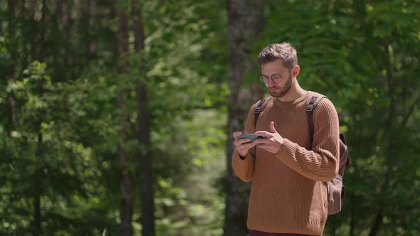 A Man Walks in the Woods and Writes a Message on His Mobile Phone