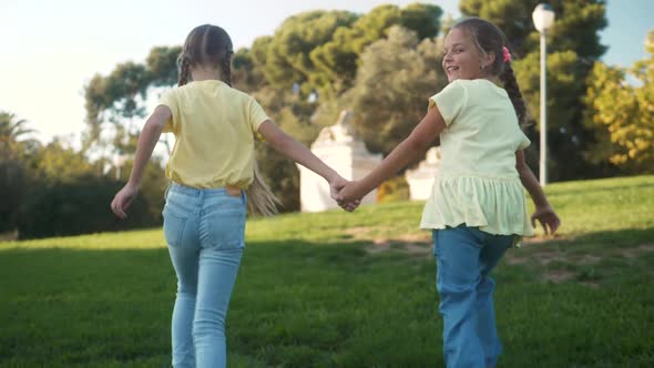 Little Girls Running in a Hedge Maze Two Sisters Kids Hold Hands and Run in Big Green Labyrinth in