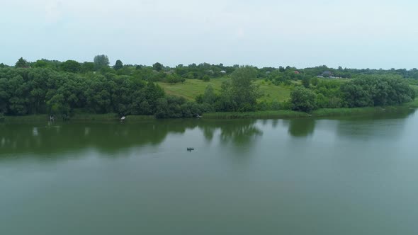 Aerial View Fisherman is Fishing Sitting on an Inflatable Boat in Lake