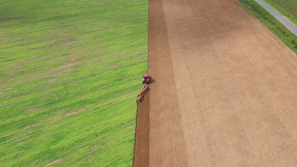 Red Tractor Ploughs A Green Field To Increase Harvest Aerial