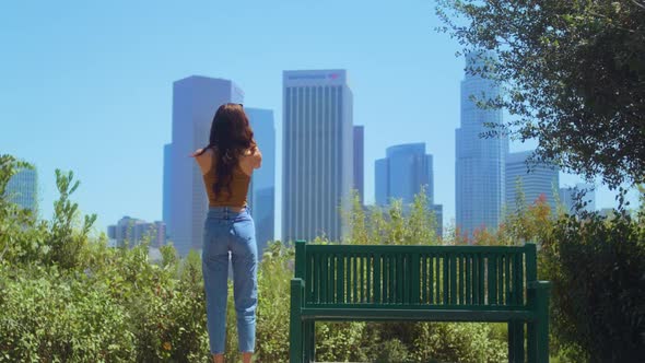 Unknown Woman Standing in Park Making Photo Skyscrapers on Smartphone Back View