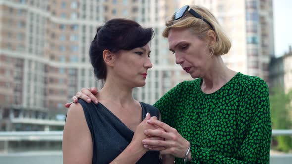 Empathetic Woman Calming Down Stressed Anxious Desperate Friend Outdoors on City Street