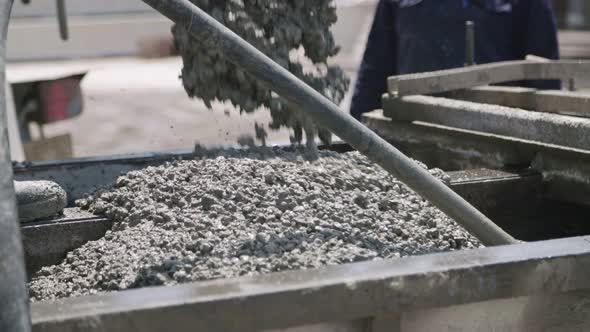 Workers pouring concrete into large steel molds on a construction site