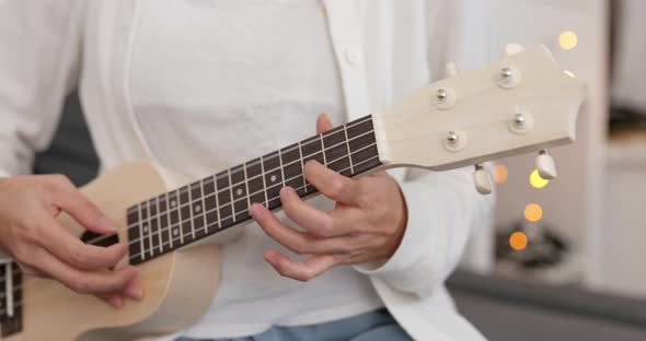 Woman play ukulele at home