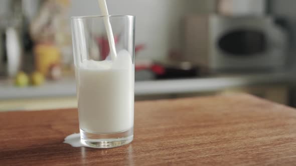 Milk is Poured into Transparent Glass The camera Moves Around the Table in the kitchen