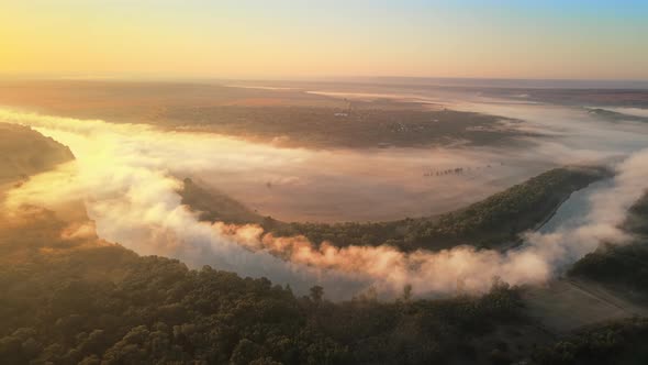 Aerial drone view of nature of Moldova at sunset. River and lush fog above it, village, greenery