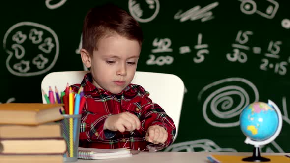 Cute child boy doing homework. Clever kid drawing at desk. Schoolboy.