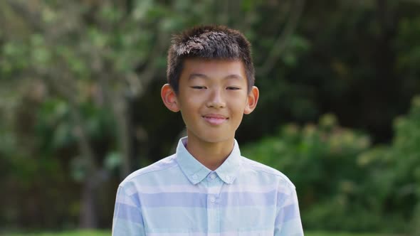 Portrait of happy asian boy looking to camera smiling and laughing in garden