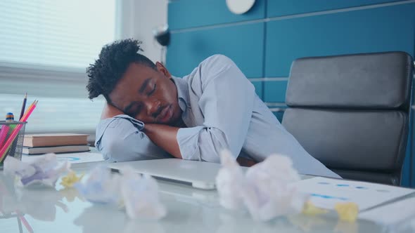 Young African American Man Sleeping Putting Head at Workplace Near Laptop