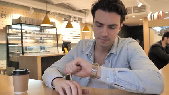 Serious Young Man Waiting While Sitting in Cafe