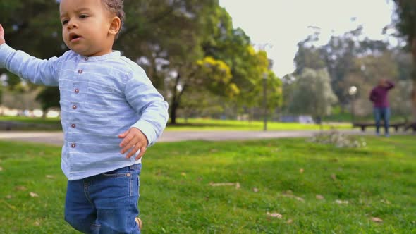 Mixed-race Boy Walking on Grass, Waving Hand, Saying Something