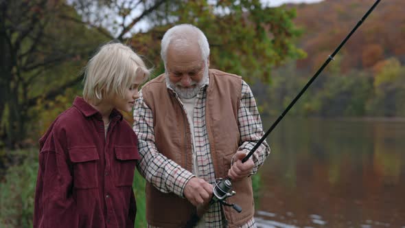 Aged Fishman Teaching His Grandson Fishing on Lake