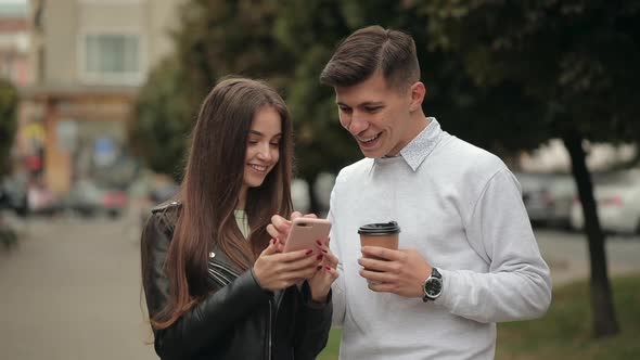 A Young Woman is Showing Photos on a Smartphone to a Man