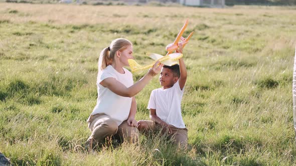 African Boy and Mother Playing Toy Plane in the Field