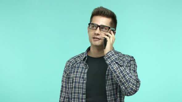 Adult Brunette Man in Casual Shirt and Glasses Talking on Mobile Phone Nodding During Conversation