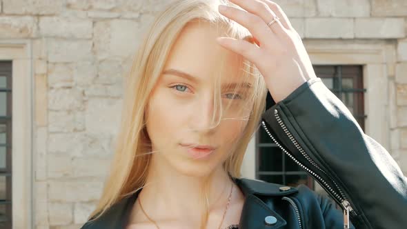 fashion portrait of a beautiful young woman with blue eyes and blonde hair in a leather jacket outdo
