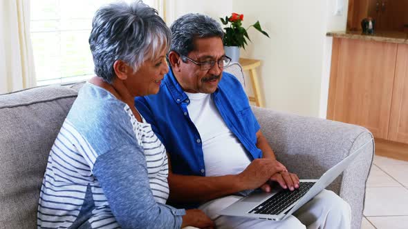 Senior couple using laptop in living room 4k