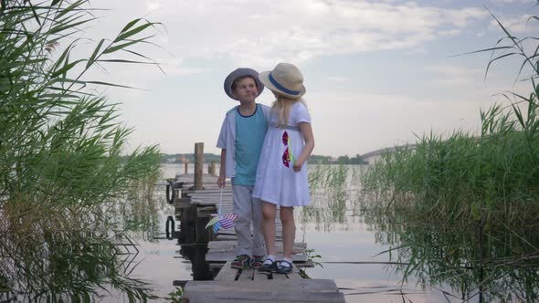 Child Relationships, Cute Beautiful Kids Boy and Girl with Toy Windmills Walk By Hand on Wooden