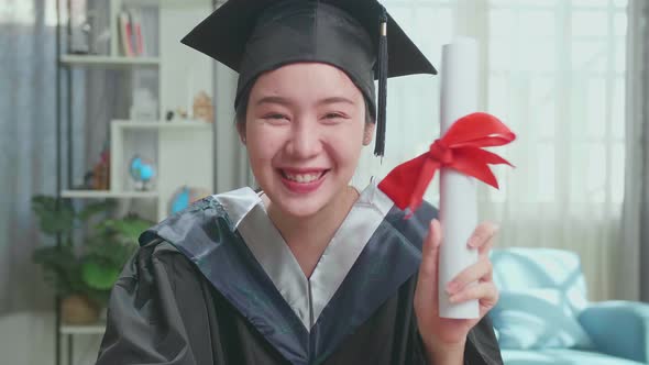 Excited Asian Woman Showing Off A University Certificate During An Online Video Call
