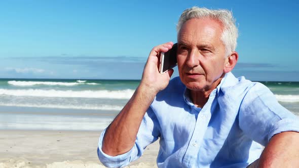 Senior man talking on mobile phone on the phone at the beach