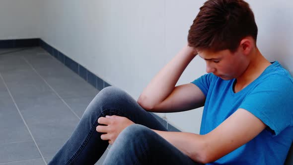 Sad schoolboy sitting in corridor