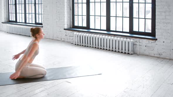 Sportive young woman in comfortable tracksuit stands in plank pose on mat