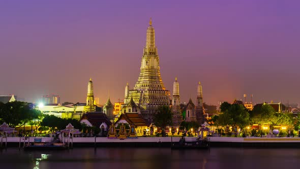 night to day time lapse of Wat Arun Temple with Chao Phraya river in Bangkok, Thailand