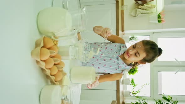 The Child Prepares the Dough in the Kitchen